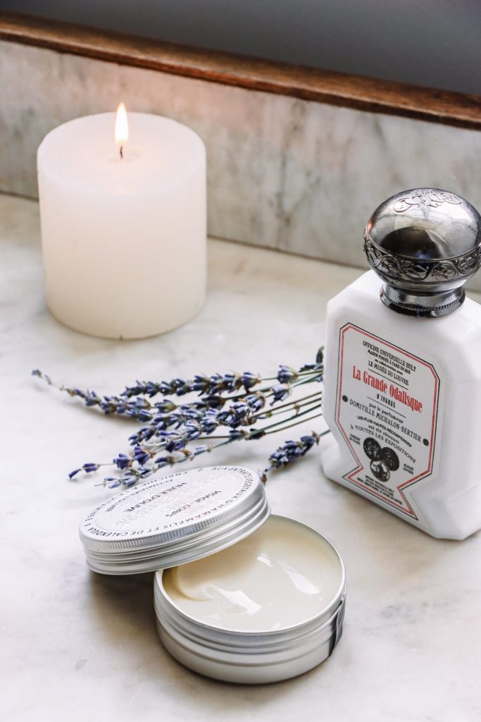 Close-up of skincare products, a sprig of lavender and a lit candle in the wellness area of the Château Les Oliviers de Salettes hotel, restaurant and spa.